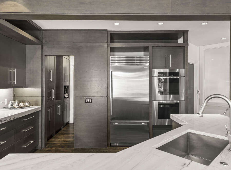 This stunning kitchen boasts a modern design with sleek, dark wood cabinetry and high-end stainless steel appliances.