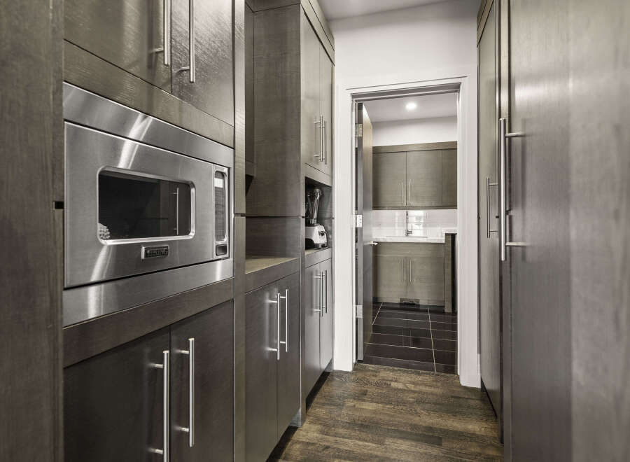 This modern kitchen boasts sleek, dark wood cabinetry and stainless steel appliances, creating a sophisticated and functional space.