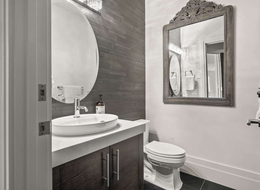 This modern bathroom features a sleek design with a dark wood vanity and a stylish round mirror.