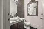 This modern bathroom features a sleek design with a dark wood vanity and a stylish round mirror.