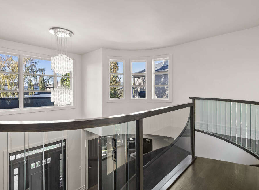 This stunning property features a grand entryway with a modern staircase and elegant glass railings.