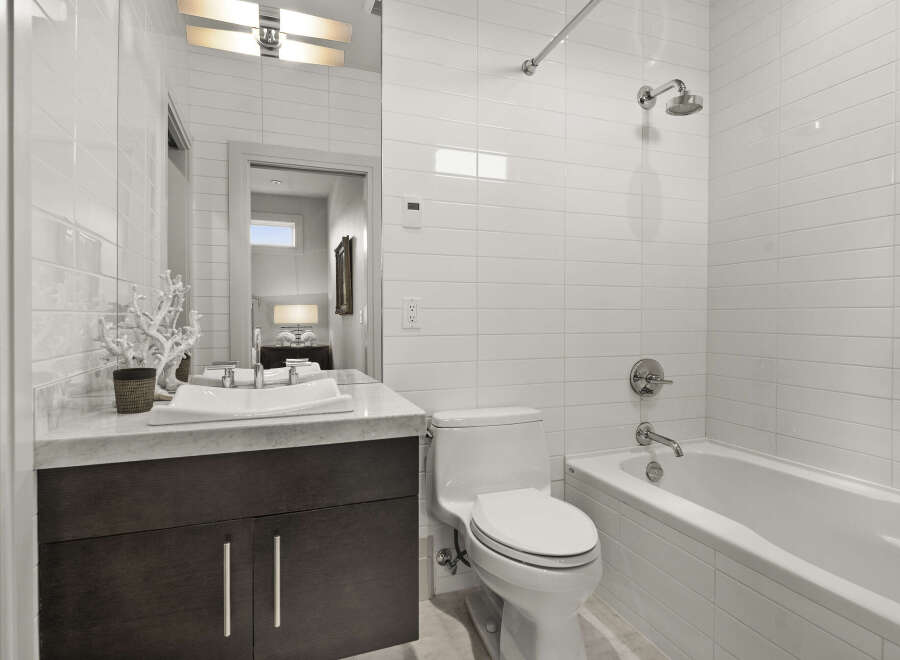 Step into a modern bathroom oasis! This stunning space boasts sleek white tile, a luxurious soaking tub, and a stylish vanity.