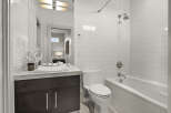 Step into a modern bathroom oasis! This stunning space boasts sleek white tile, a luxurious soaking tub, and a stylish vanity.