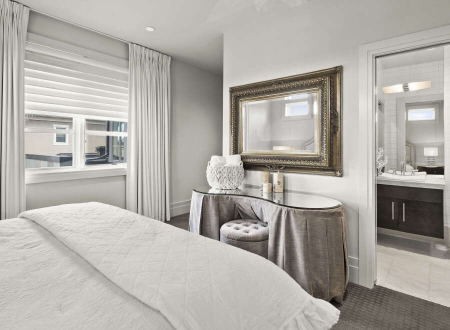 Step into luxury with this stunning bedroom, featuring a beautifully designed vanity area and a glimpse into a modern bathroom.