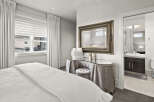 Step into luxury with this stunning bedroom, featuring a beautifully designed vanity area and a glimpse into a modern bathroom.