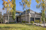 This stunning property boasts a modern architectural design with a sleek exterior and lush landscaping.