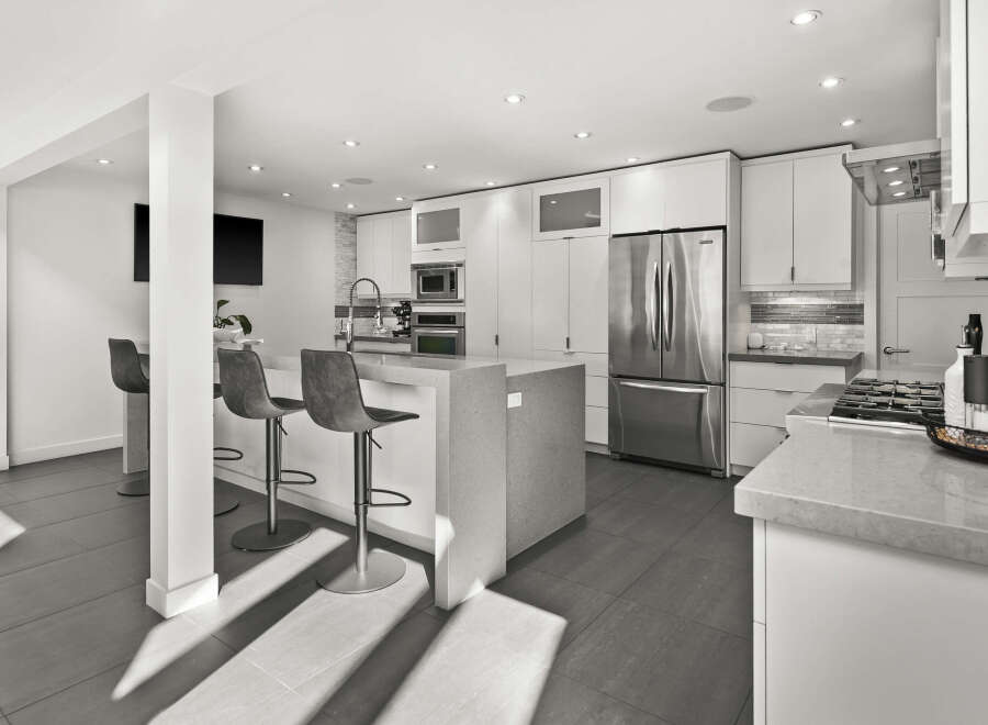 This stunning modern kitchen boasts sleek white cabinetry, stainless steel appliances, and a spacious island with seating.