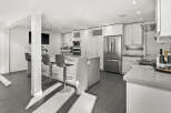 This stunning modern kitchen boasts sleek white cabinetry, stainless steel appliances, and a spacious island with seating.