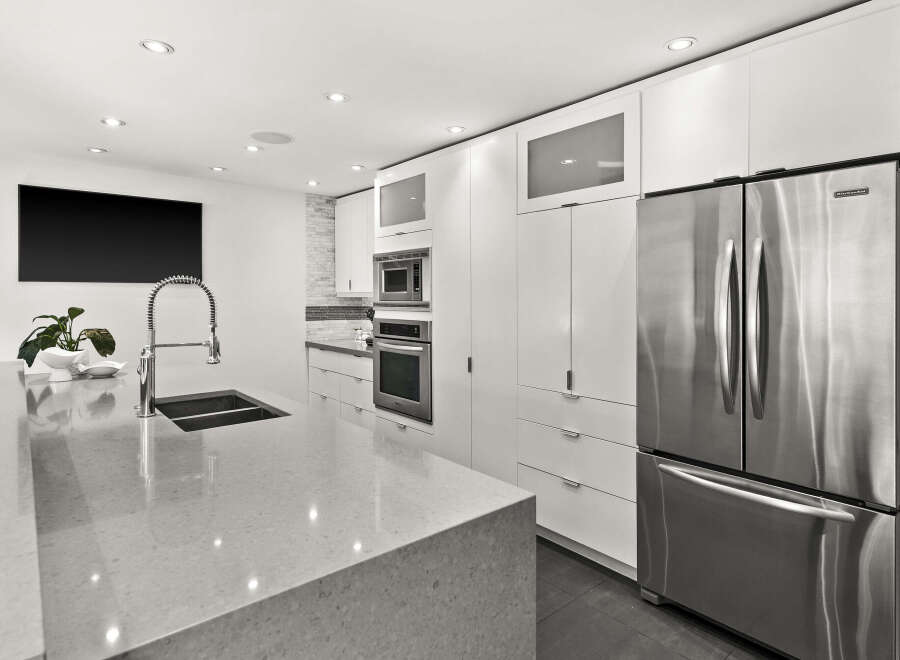 This modern kitchen boasts sleek, white cabinetry and stainless steel appliances, creating a bright and inviting space.