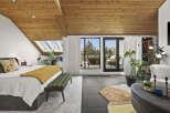 This stunning bedroom boasts a unique design with a wooden slatted ceiling and large windows that offer breathtaking views.