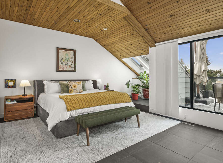 This stunning bedroom boasts a unique design with a sloped wooden ceiling, creating a warm and inviting atmosphere.