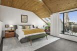 This stunning bedroom boasts a unique design with a sloped wooden ceiling, creating a warm and inviting atmosphere.