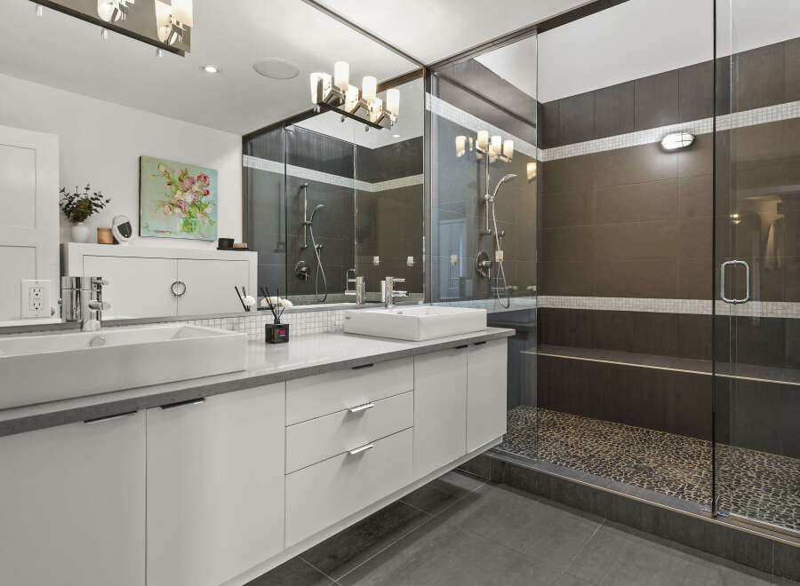 This stunning bathroom boasts a modern design with sleek white cabinetry and a luxurious double vanity.