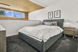 This modern bedroom boasts a cozy ambiance with its plush gray carpet and a comfortable bed.