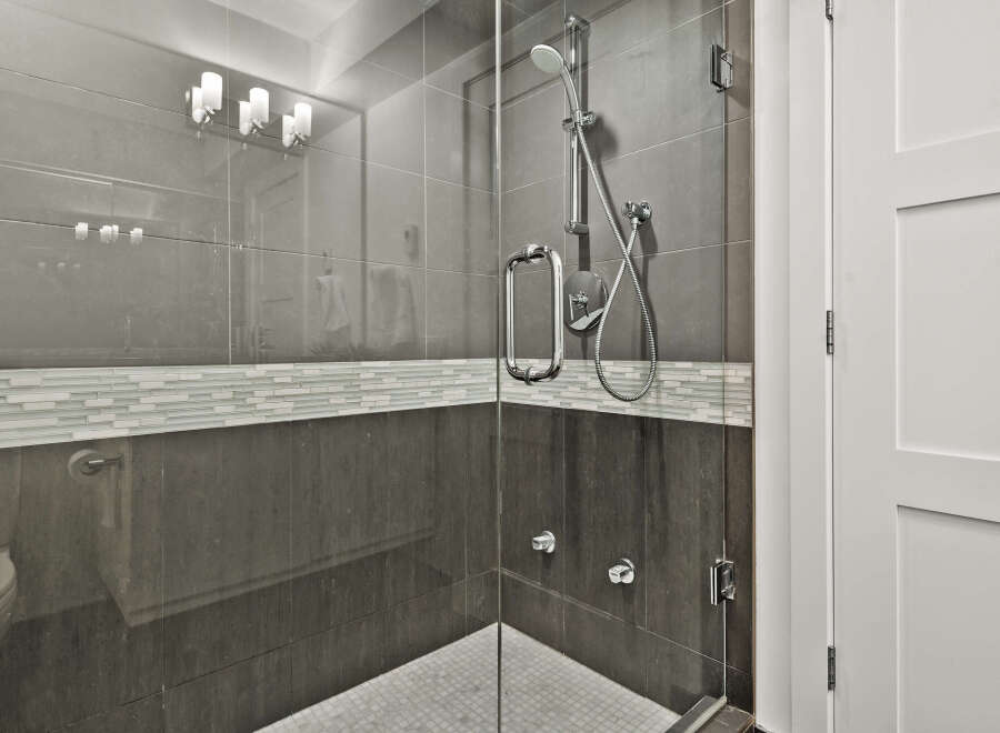 Step into a modern bathroom oasis! This stunning space features a sleek glass shower enclosure with a rainfall showerhead and stylish tile accents.