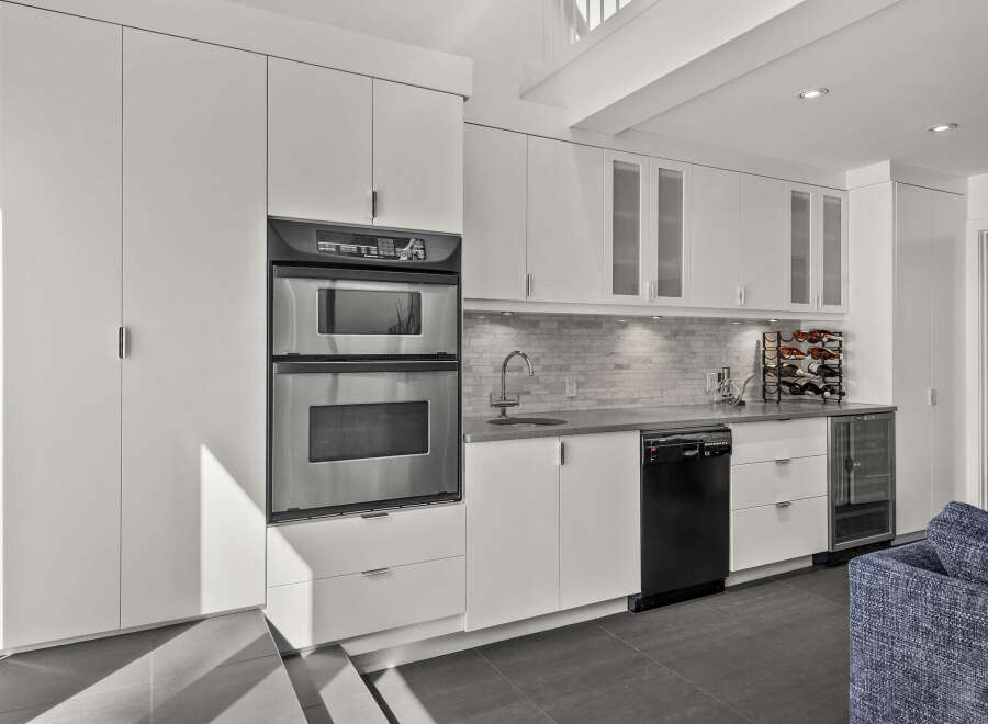 This modern kitchen boasts sleek, white cabinetry and stainless steel appliances, creating a clean and contemporary aesthetic.