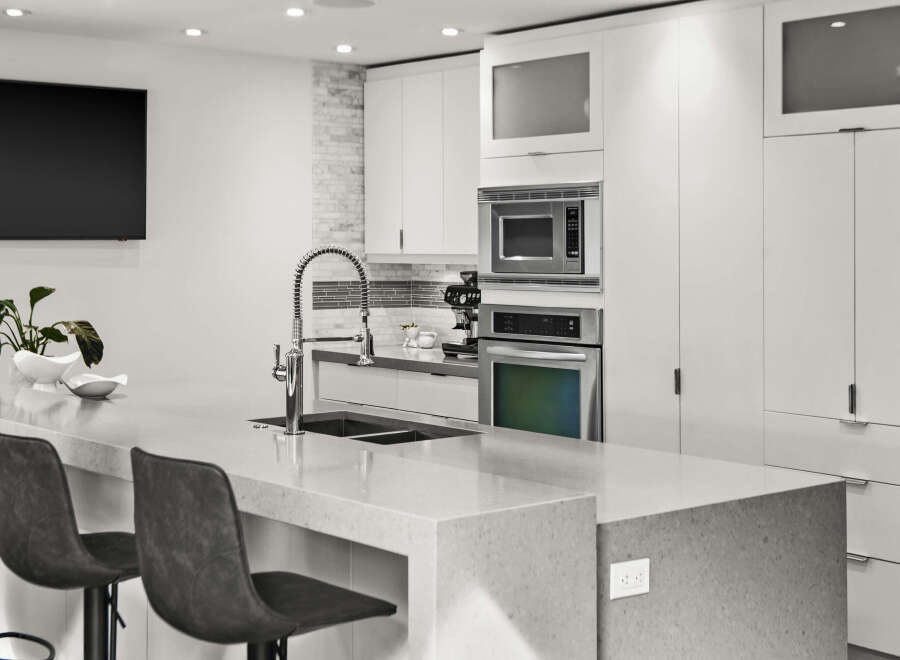 This modern kitchen boasts sleek, white cabinetry and a spacious countertop, perfect for culinary endeavors and entertaining.