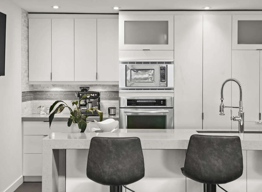 This modern kitchen boasts sleek, white cabinetry and stainless steel appliances, creating a clean and contemporary aesthetic.