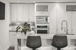 This modern kitchen boasts sleek, white cabinetry and stainless steel appliances, creating a clean and contemporary aesthetic.