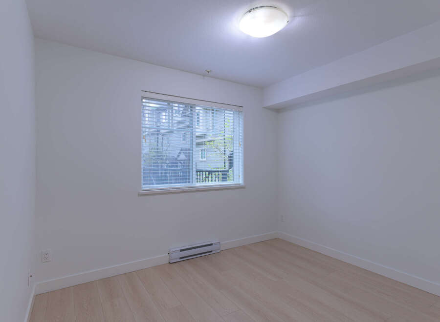 This bright and airy room features a large window with blinds, allowing for ample natural light.
