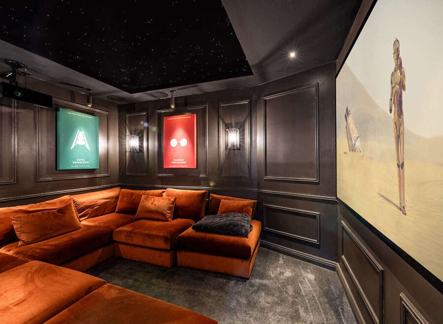 Step into luxury with this stunning home theater! Featuring a plush, orange sectional sofa, a starry ceiling, and movie posters, this space is designed for ultimate relaxation and entertainment.