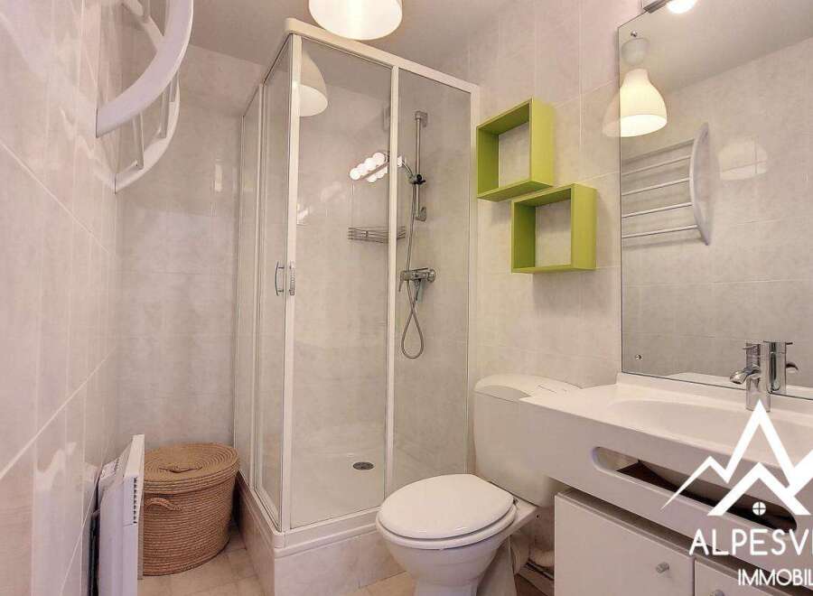 Discover this modern bathroom featuring a sleek shower enclosure and stylish green shelving.