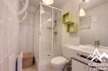 Discover this modern bathroom featuring a sleek shower enclosure and stylish green shelving.
