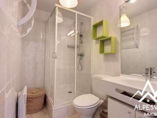 Discover this modern bathroom featuring a sleek shower enclosure and stylish green shelving.