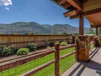 Enjoy breathtaking mountain views from this stunning property, featuring a spacious backyard with a wooden fence and lush green lawn.