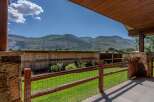 Experience breathtaking mountain views from this stunning property, framed by a rustic wooden fence and a covered patio.