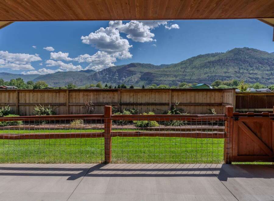 Enjoy breathtaking mountain views from this stunning property, framed by a rustic wooden fence and gate.
