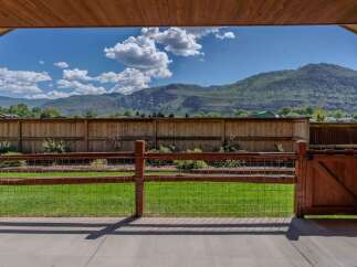 Enjoy breathtaking mountain views from this stunning property, framed by a rustic wooden fence and gate.