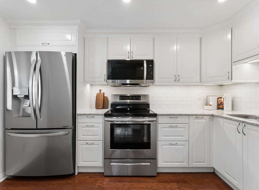 This stunning kitchen boasts modern stainless steel appliances, including a refrigerator, microwave, and oven.