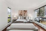 Experience luxury in this stunning bedroom featuring a cozy bed, elegant artwork, and ample natural light.