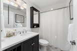 This modern bathroom features a sleek vanity with a white countertop and dark cabinetry, offering ample storage and a stylish contrast.