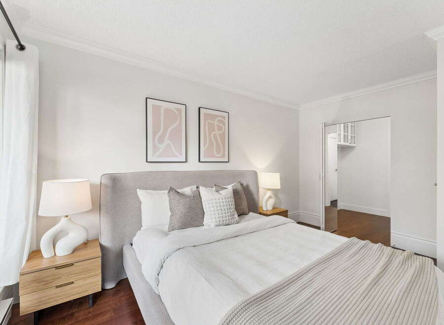 Step into this serene bedroom, featuring a plush bed with a stylish headboard and a cozy throw blanket.