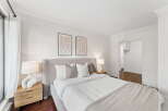 Step into this serene bedroom, featuring a plush bed with a stylish headboard and a cozy throw blanket.