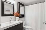 This modern bathroom features a sleek vanity with a dark wood finish, complemented by a stylish mirror and a decorative plant.