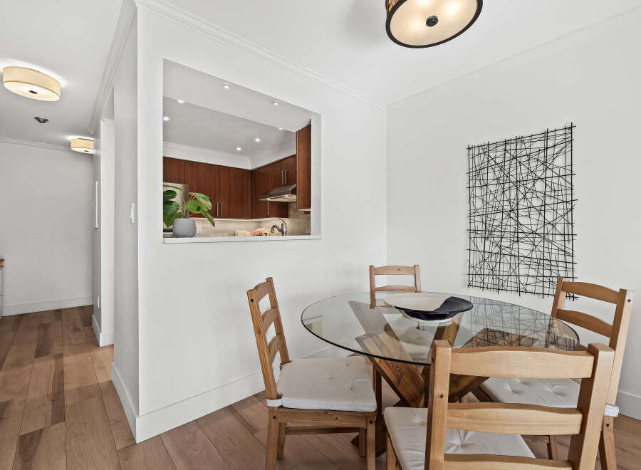 This stunning dining area features a modern glass-top table and stylish wooden chairs, perfect for hosting gatherings.