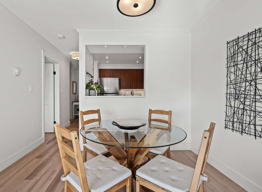 This stunning dining area features a modern glass-top table and four wooden chairs, perfect for intimate gatherings.