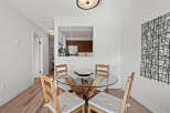 This stunning dining area features a modern glass-top table and four wooden chairs, perfect for intimate gatherings.