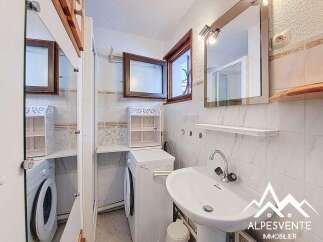 This charming bathroom features a modern design with a sleek sink and a convenient washing machine.
