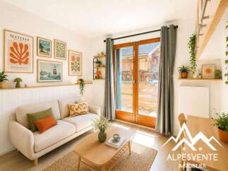This charming living room features a cozy beige sofa adorned with decorative pillows, complemented by a light wood coffee table and a textured rug.