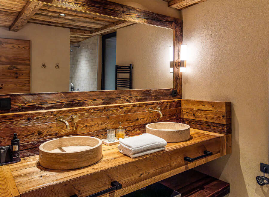 Experience rustic elegance in this stunning bathroom, featuring a custom wooden vanity with dual stone sinks.