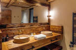 Experience rustic elegance in this stunning bathroom, featuring a custom wooden vanity with dual stone sinks.