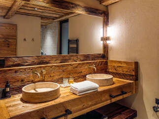 Experience rustic elegance in this stunning bathroom, featuring a custom wooden vanity with dual stone sinks.