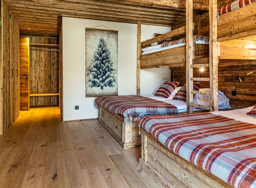 Experience rustic charm in this stunning bedroom featuring custom-built wooden bunk beds and a cozy, inviting atmosphere.