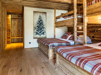 Experience rustic charm in this stunning bedroom featuring custom-built wooden bunk beds and a cozy, inviting atmosphere.