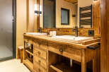 This stunning bathroom features a custom wooden vanity with dual sinks, offering ample space and a touch of rustic elegance.