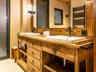 This stunning bathroom features a custom wooden vanity with dual sinks, offering ample space and a touch of rustic elegance.